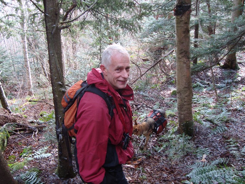 Man and tiny dog attached by snout to jacket