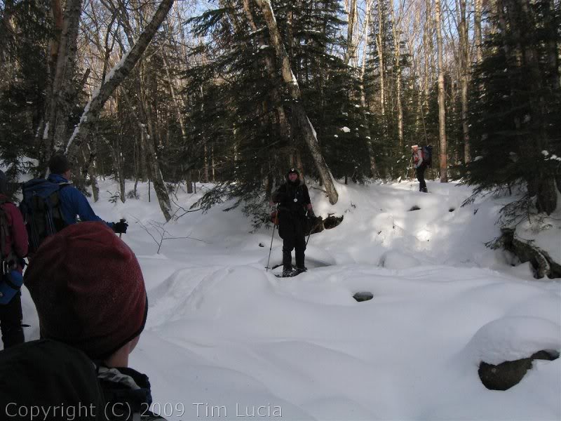 Hiker Ed testing a snow bridge by standing on it and ta...